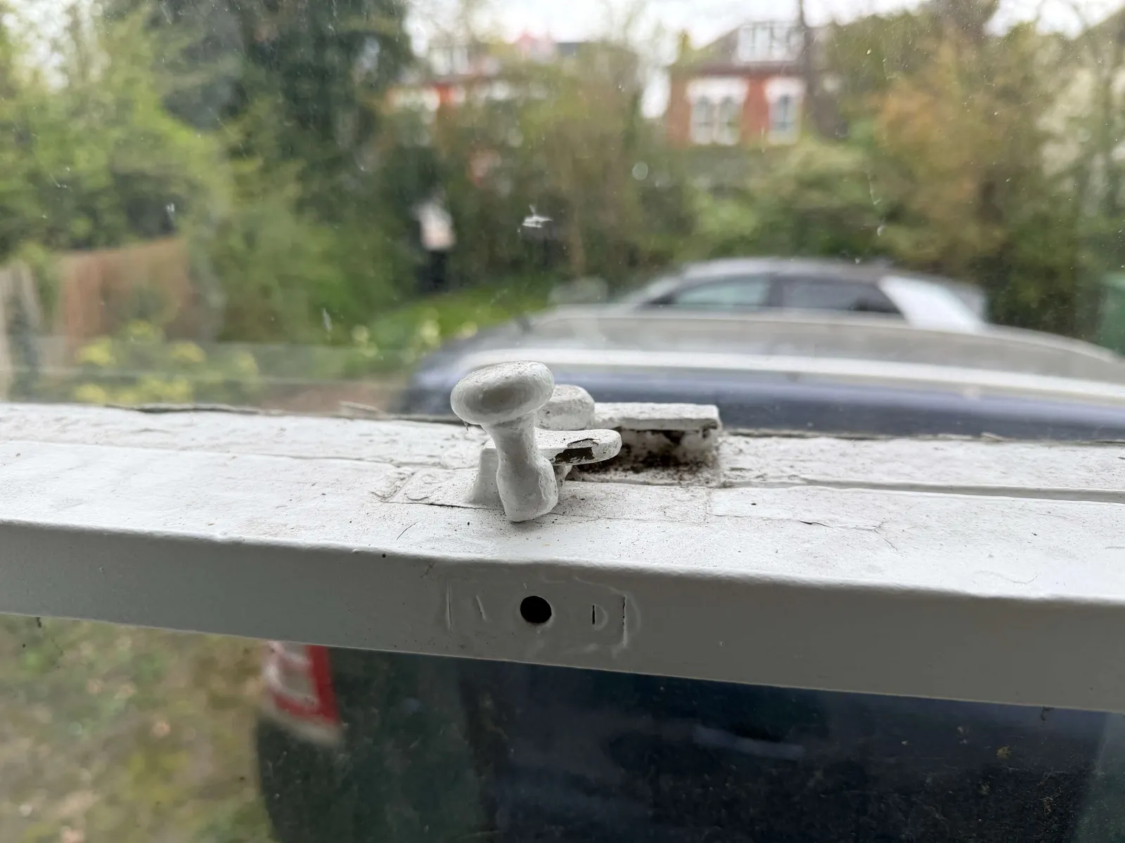 A traditional Fitch-style sash window fastener buried under multiple layers of paint, common on historic windows that haven't been restored